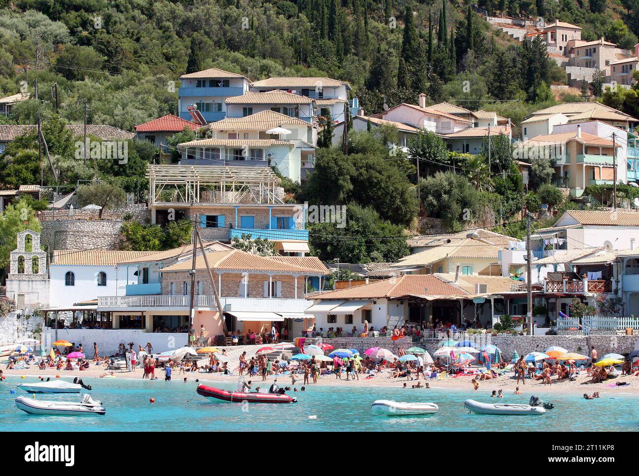 Agios Nikitas villaggio di pescatori, Lefkada (Lefkas), Isole Ionie, Grecia. Ampia panoramica della trafficata spiaggia del villaggio che mostra la tipica attività di vacanza in famiglia Foto Stock