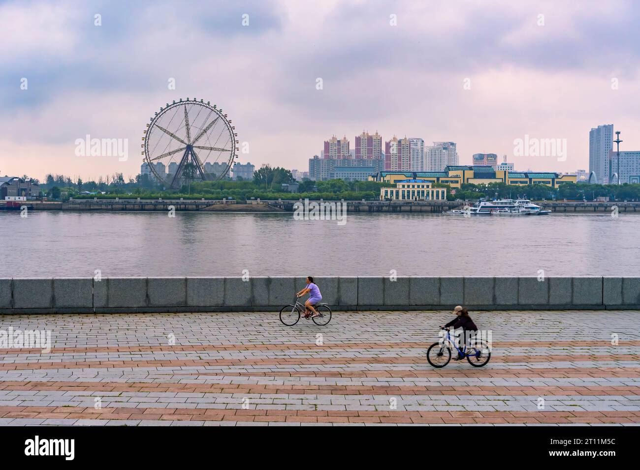 Pechino, Russia. 24 luglio 2023. Due donne vanno in bicicletta lungo l'argine del fiume Amur a Blagoveshchensk, Russia, 24 luglio 2023. La città cinese di Heihe si affaccia sulla città russa di Blagoveshchensk attraverso il fiume Heilongjiang, noto in Russia come fiume Amur. Nel giugno dello scorso anno, il ponte autostradale transfrontaliero Heihe-Blagoveshchensk sul fiume Heilongjiang si è aperto al traffico. Il ponte ha svolto un ruolo importante nell'aumento del fatturato commerciale e ha aperto una nuova pagina nello sviluppo delle relazioni bilaterali. Crediti: Guo Feizhou/Xinhua/Alamy Live News Foto Stock