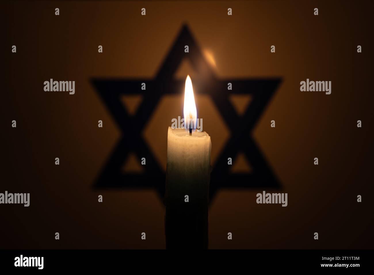 Candela brucia sullo sfondo della bandiera di Israele. Giornata internazionale della memoria dell'Olocausto, gennaio 27. Guerra in Medio Oriente Foto Stock