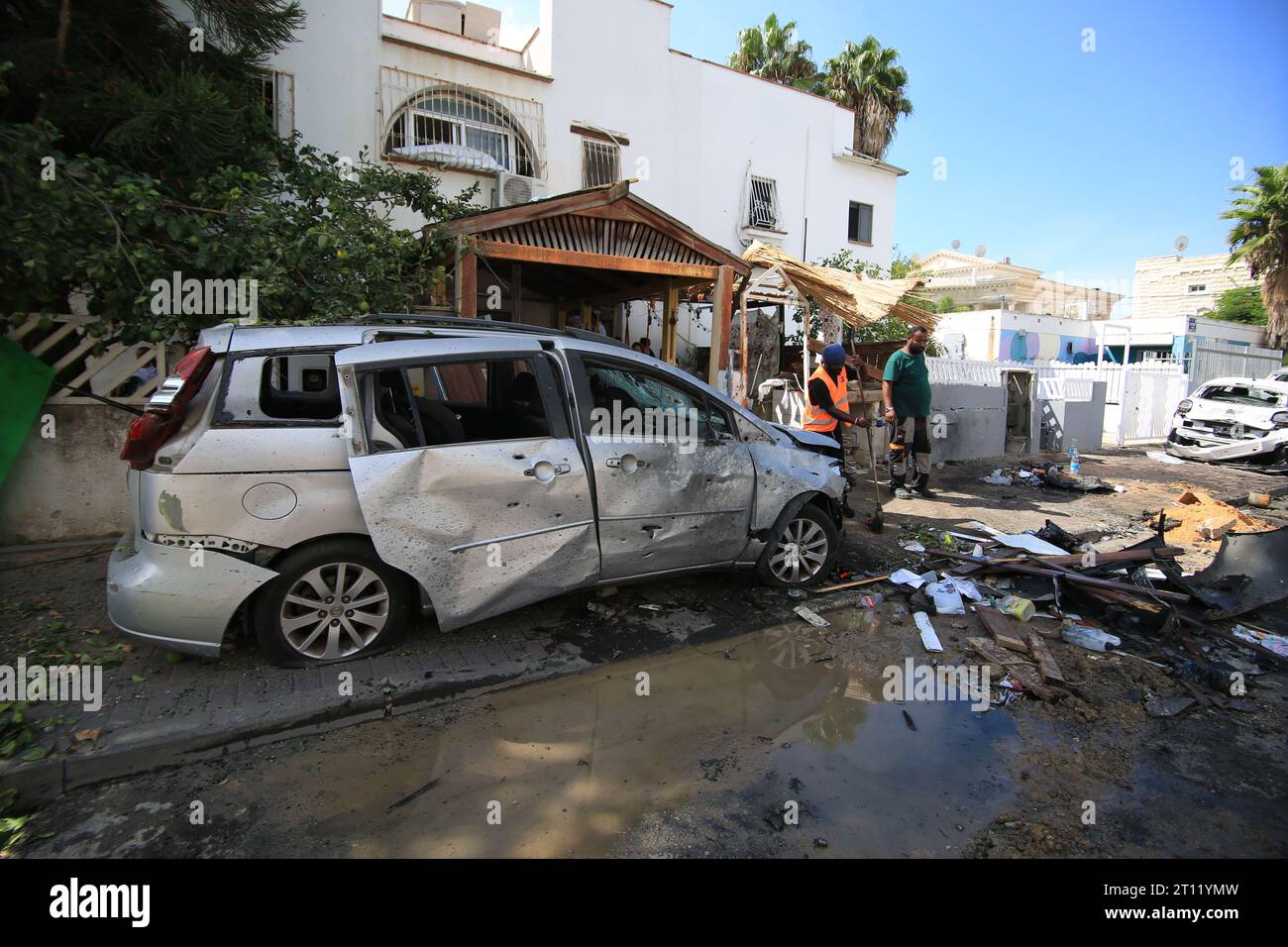 La gente ha visto pulire il caos nelle loro strade intorno alle auto danneggiate dopo il lancio con razzi da parte dei palestinesi in risposta agli attacchi aerei israeliani durante un'operazione a Ramla. I combattimenti tra soldati israeliani e militanti islamici di Hamas continuano nella zona di confine con Gaza. Sconvolto dall'assalto senza precedenti sul suo territorio, un Israele in lutto ha contato oltre 700 morti e ha lanciato un'appassionante raffica di scioperi a Gaza che hanno portato il bilancio delle vittime a 493 secondo i funzionari palestinesi. Foto Stock