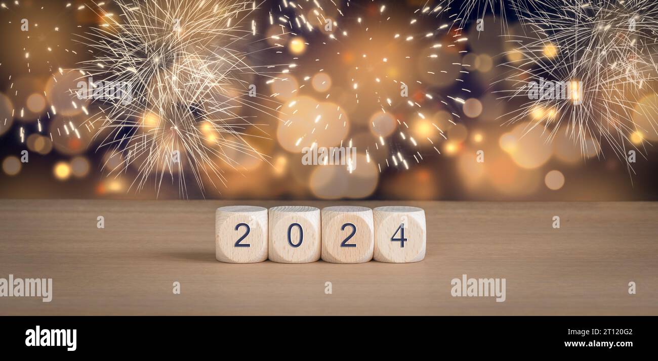 Cubi di legno con Capodanno 2024 e fuochi d'artificio su sfondo bokeh. Foto Stock