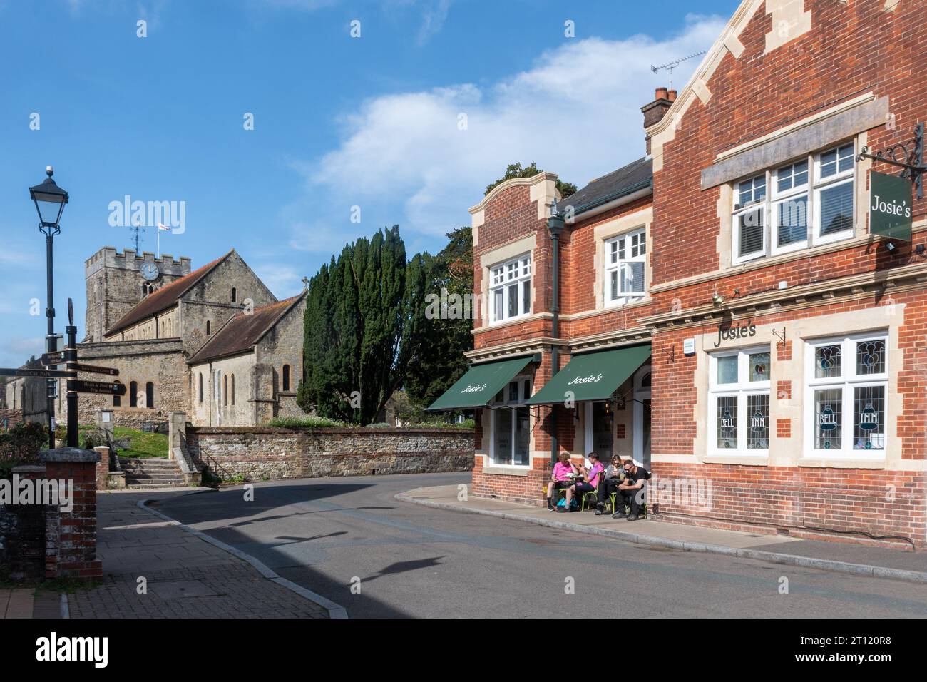 Chiesa di San Pietro a Petersfield, Hampshire, Inghilterra, Regno Unito, vista da St Peter's Road, con persone sedute fuori dalla caffetteria Josie's. Foto Stock