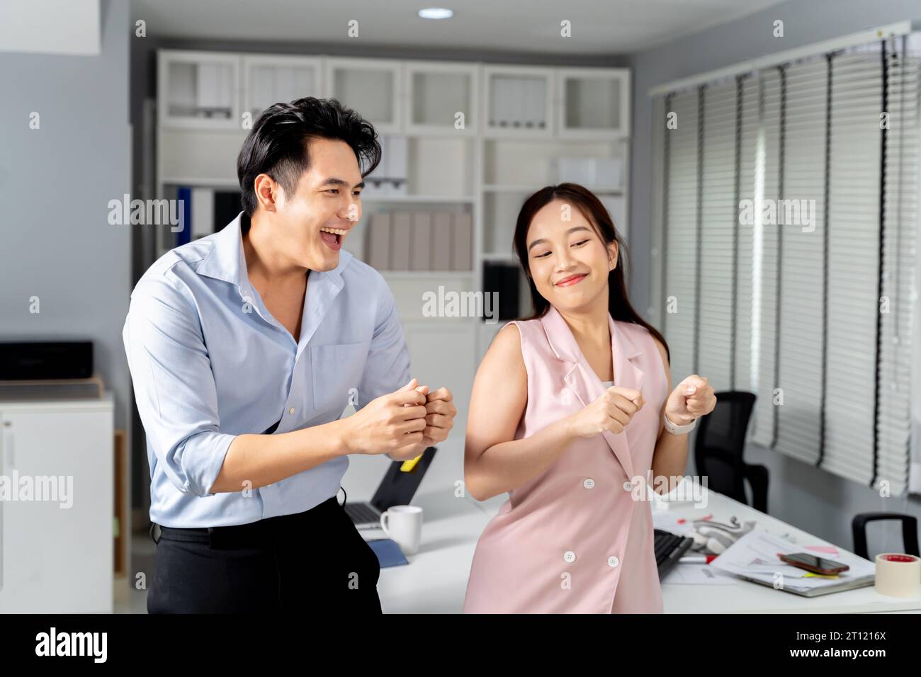 Felicissimo uomo d'affari e donna d'affari asiatica sorridendo e ballando con felicità e celebrando il successo in ufficio. - Un posto di lavoro di successo e divertente Foto Stock