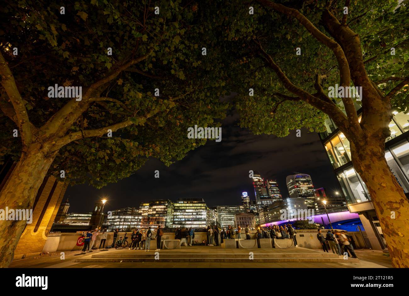 Londra, Regno Unito: Vista notturna della città di Londra dalla riva sud del Tamigi vicino al London Bridge a Southwark. Persone in primo piano. Foto Stock