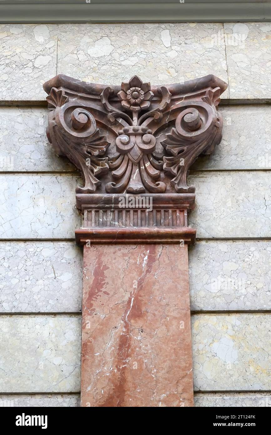 Colonna in marmo rosa e la sua struttura decorativa a capitale nella facciata dell'edificio storico. Foto Stock
