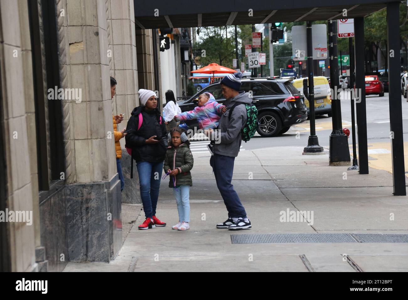 Le famiglie e i bambini migranti si fermano fuori dall'Inn di Chicago, a pochi passi dal Magnificent Mile e dal quartiere finanziario centrale, come visto qui il 10 ottobre 2022. Per oltre un anno, l'Inn of Chicago ha ospitato oltre 1.500 nuovi arrivi, questo ex hotel boutique è circondato da hotel di lusso, ristoranti ed è una delle principali aree turistiche. Due consiglieri del centro chiedono la chiusura di questo rifugio, citando crescenti lamentele da parte dei vicini. (Foto di: Alexandra Buxbaum/Sipa USA) credito: SIPA USA/Alamy Live News Foto Stock