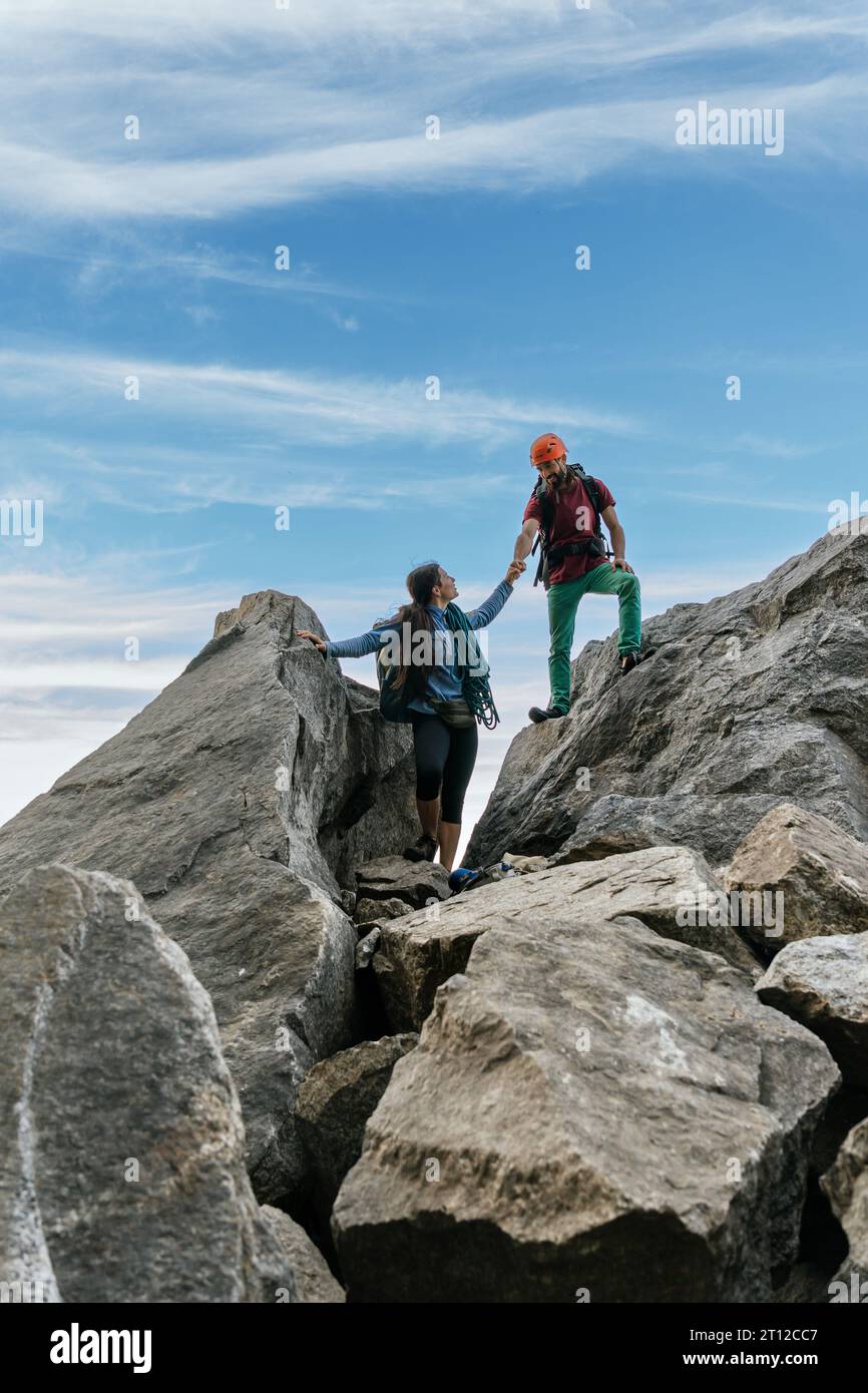 Alpinisti maschili e femminili in cima alla montagna. Squadra di arrampicata su roccia mista. Foto Stock