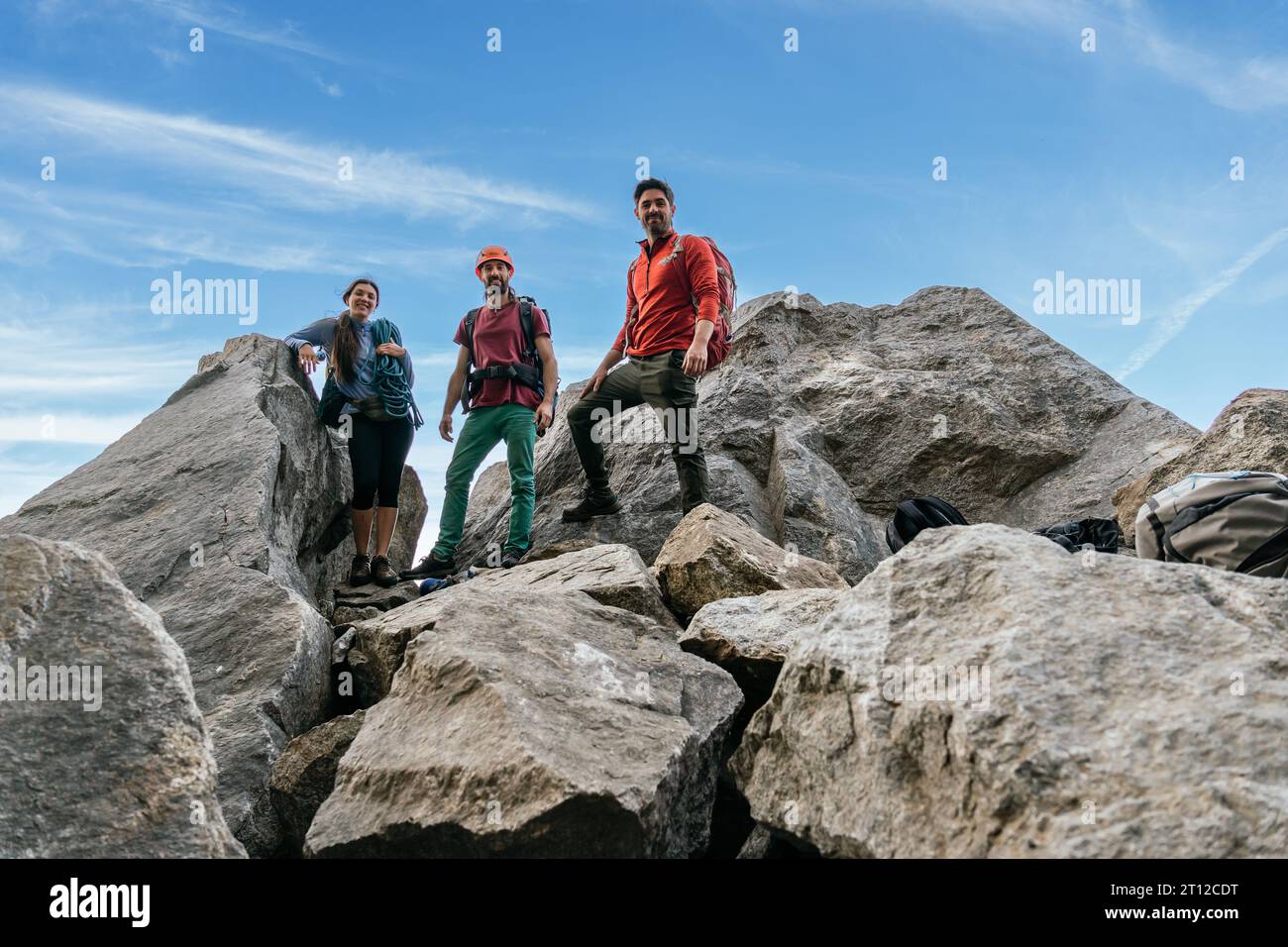 Un gruppo di amici che si arrampicano sorridendo e guardando la telecamera in cima alla roccia. Squadra di arrampicata su roccia mista. Foto Stock