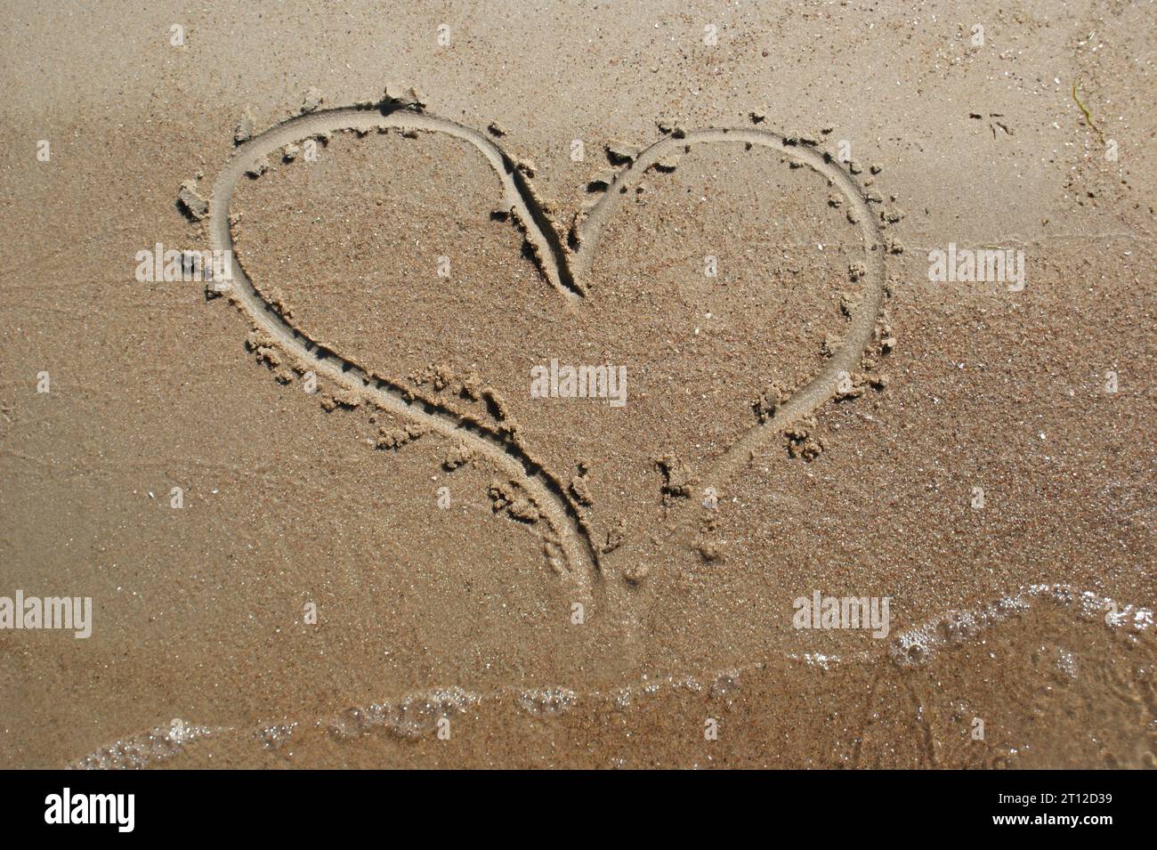 Un cuore disegnato su sabbia bagnata. Amore e sentimenti. Foto Stock