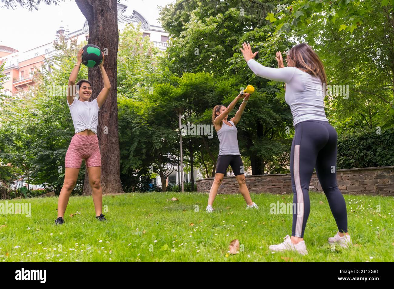 Ragazza latina che fa esercizio fisico e sport in un parco verde, istruttrice insegna alle studentesse con esercizi di pesi Foto Stock