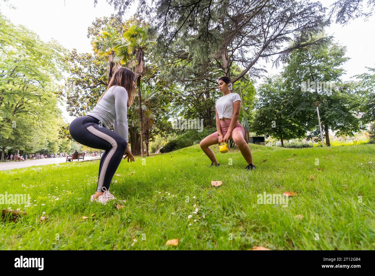 Ragazza latina che fa esercizio fisico e sport in un parco verde, istruttrice insegna alle studentesse con esercizi di pesi Foto Stock