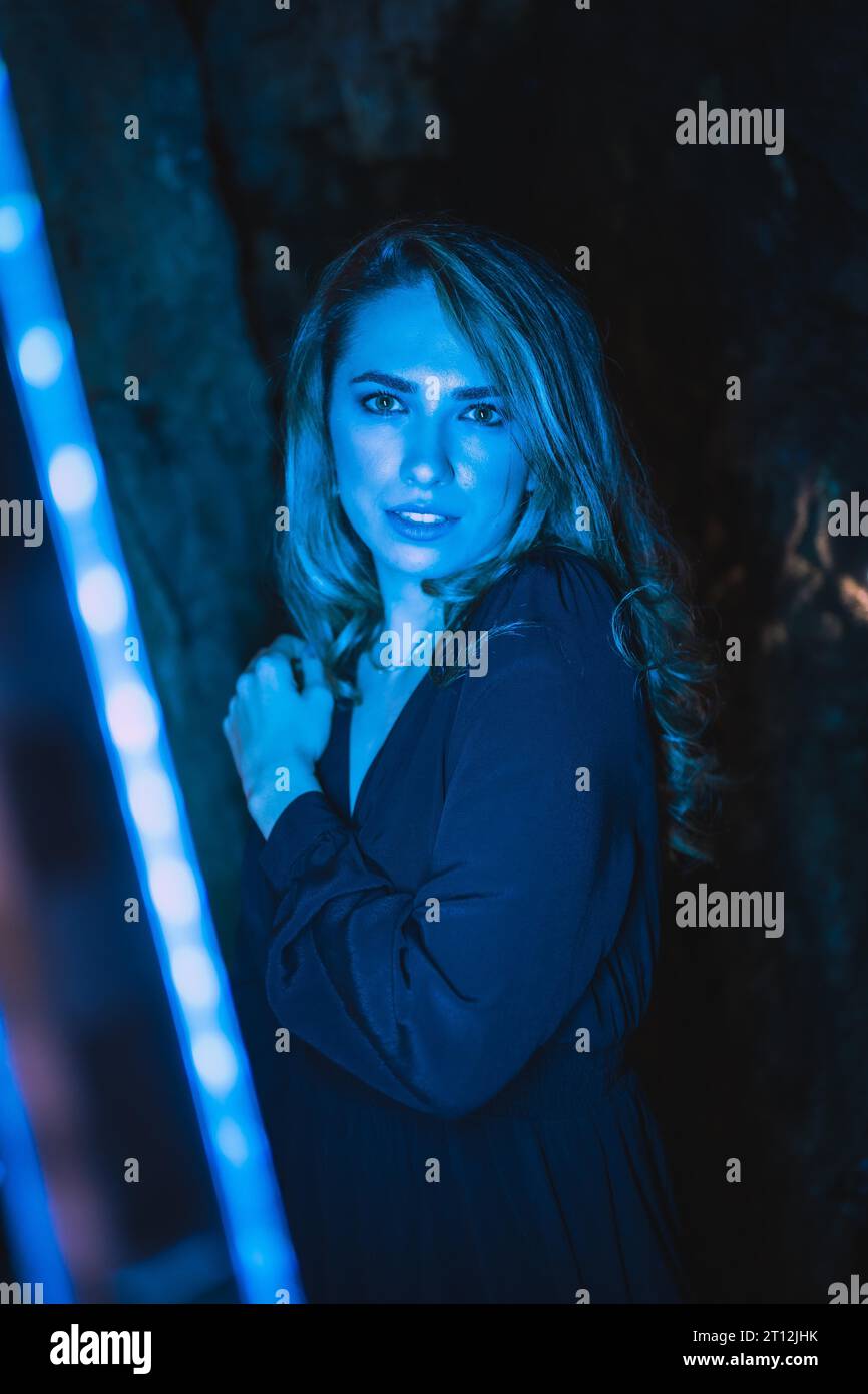 Stile di vita, ritratto di una ragazza caucasica in una grotta con luce LED blu Foto Stock