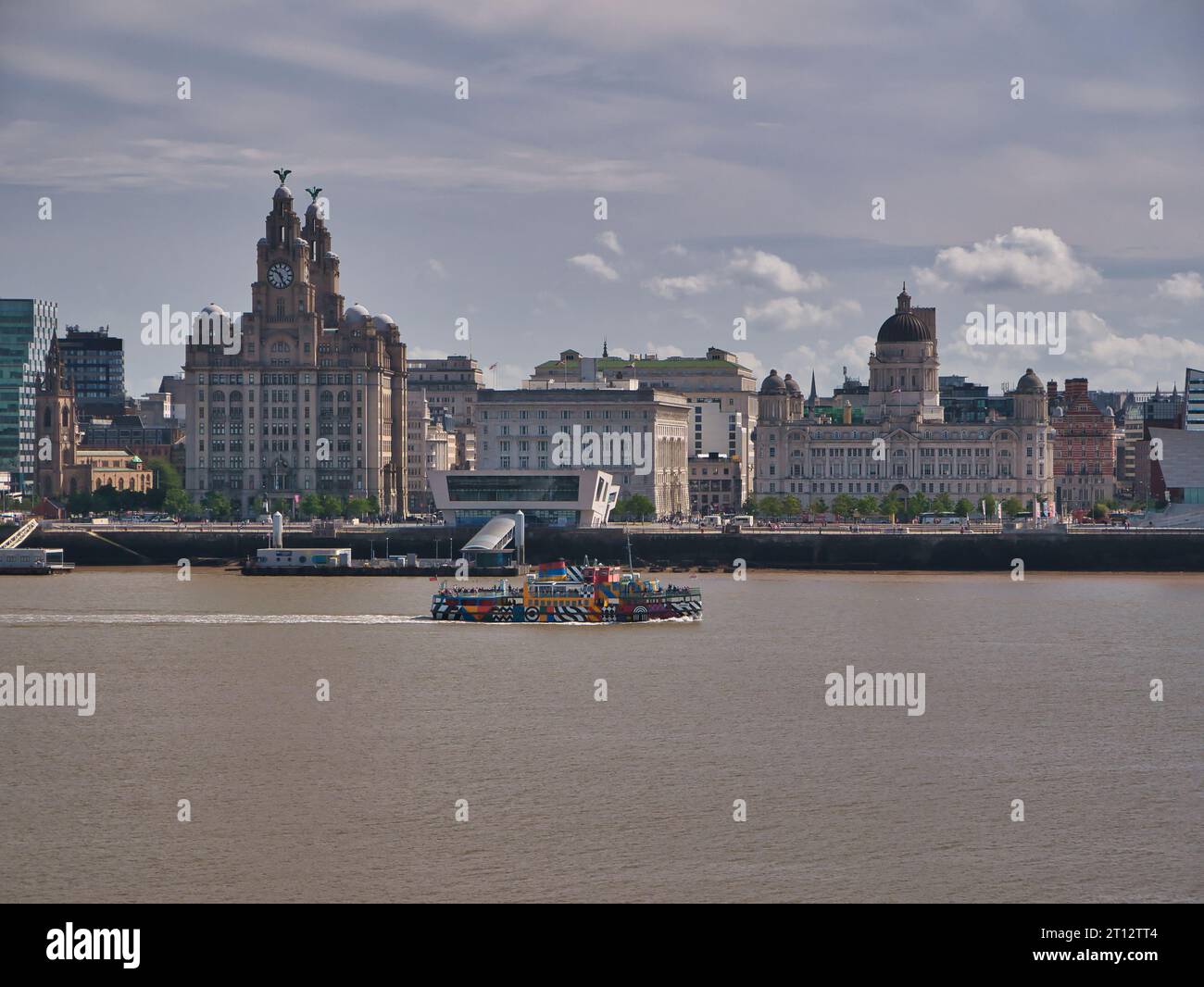 La discesa sul traghetto per il fiume Mersey passa per le Three Graces sullo storico lungomare di Liverpool. Il disegno artistico è di Sir Peter Blake. Foto Stock