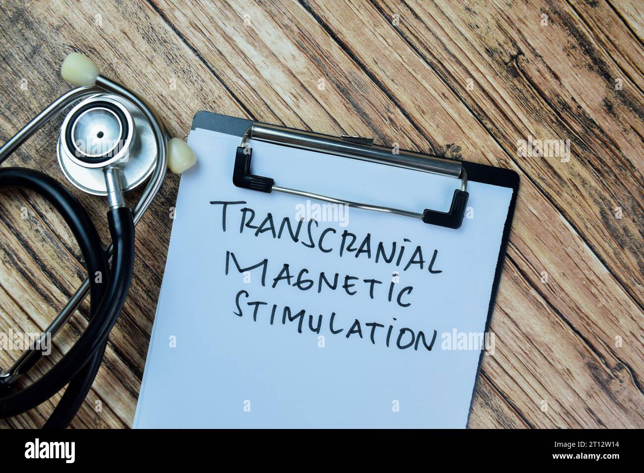Concetto di stimolazione magnetica transcranica scrittura su documenti isolati su un tavolo di legno. Foto Stock