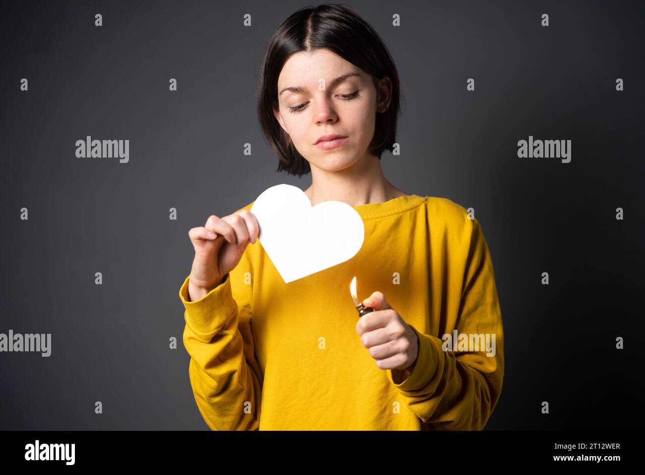 Una ragazza con maglione giallo dà fuoco al cuore. Foto Stock