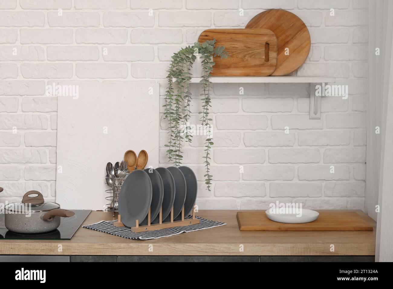 Ripiani in legno con portapiastre, tagliere, utensili e fornelli elettrici in una cucina moderna Foto Stock