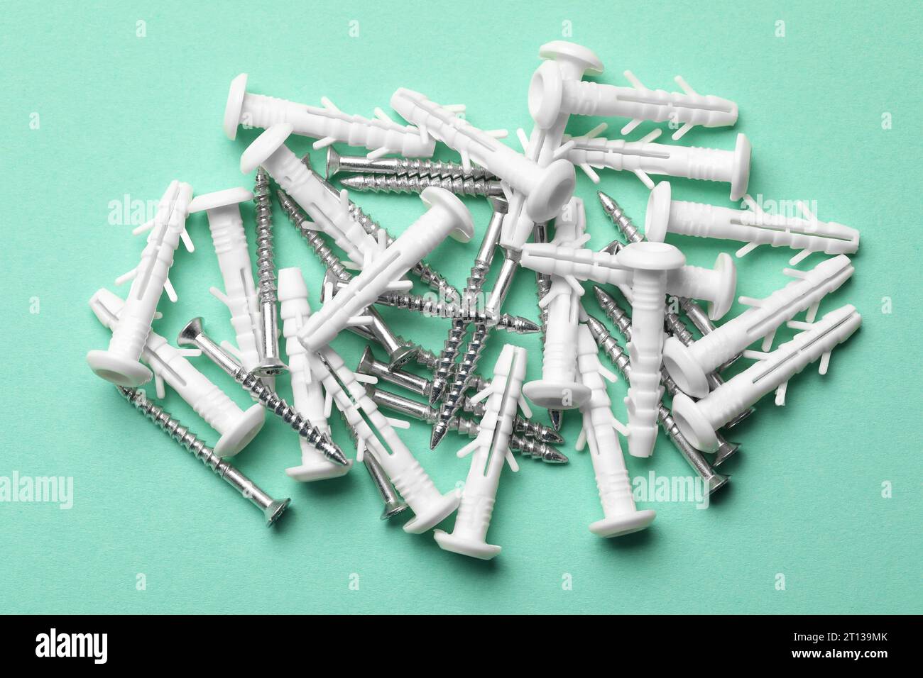 Molte viti in metallo e tasselli bianchi su sfondo turchese, sono piatti Foto Stock