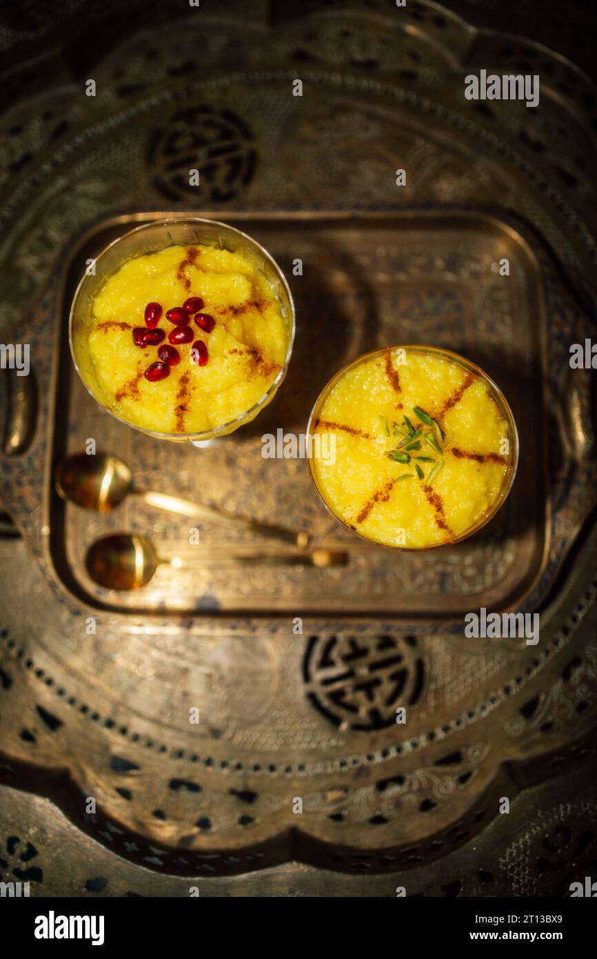 Sholeh Zard, un dessert persiano di riso allo zafferano condito con cannella, pistacchi, melograno su ottone, tavolo Foto Stock