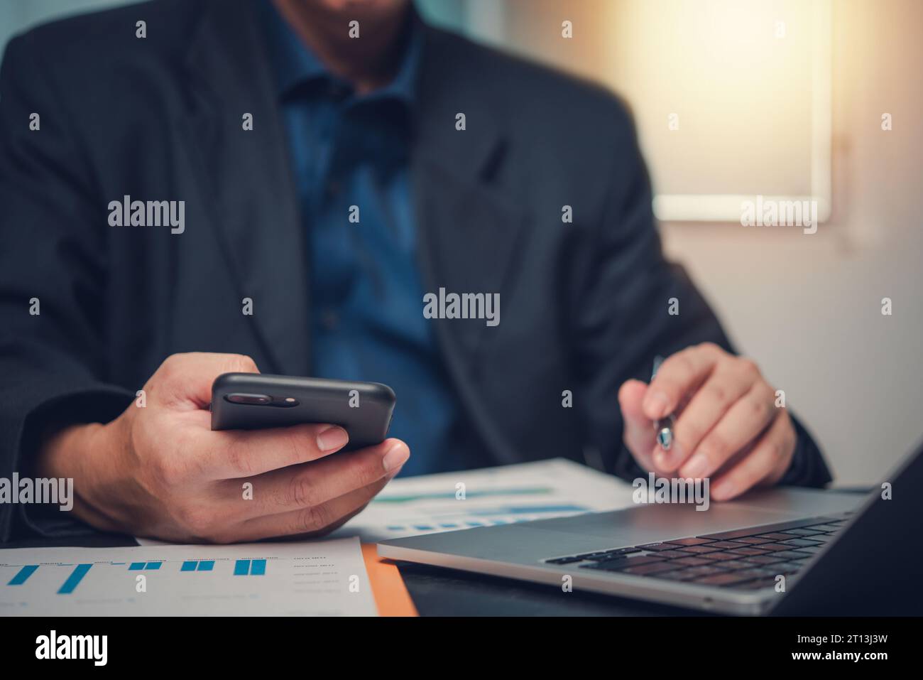 Uomo d'affari che analizza i dati su laptop e grafico per la pianificazione finanziaria, segnala il marketing su scrivania. Foto Stock
