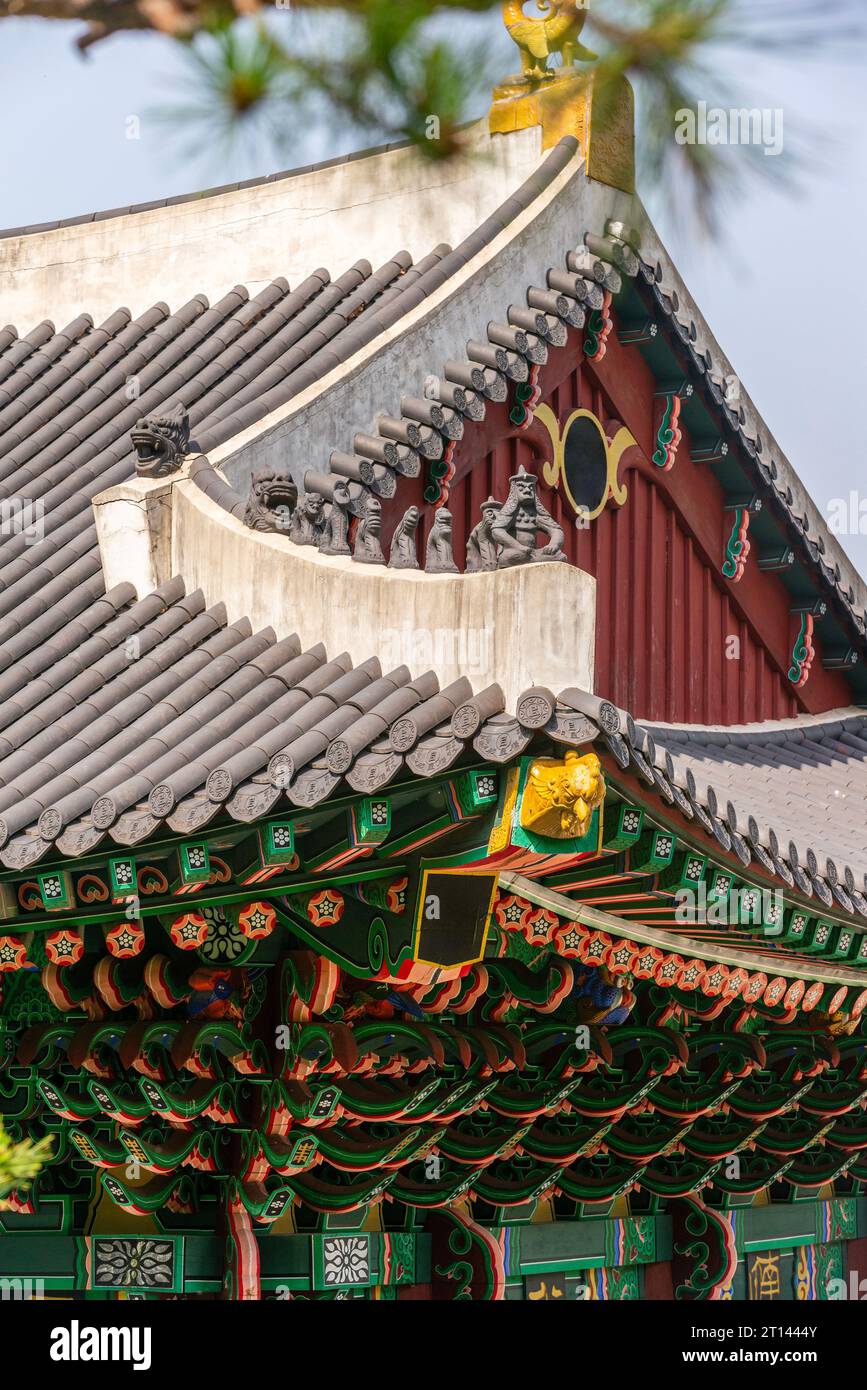 Tradizionale dipinto multicolore sulle gronde di una vecchia casa con Jabsang seduto su un tetto di tegole Foto Stock