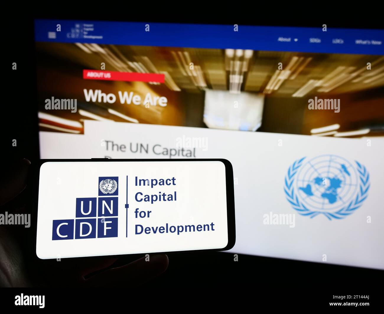 Persona che possiede uno smartphone con il logo del Fondo delle Nazioni Unite per lo sviluppo del capitale (UNCDF) davanti al sito Web. Concentrarsi sul display del telefono. Foto Stock