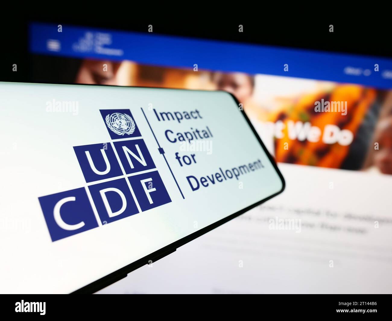 Telefono cellulare con logo del Fondo delle Nazioni Unite per lo sviluppo del capitale (UNCDF) davanti al sito web. Mettere a fuoco il display centrale sinistro del telefono. Foto Stock