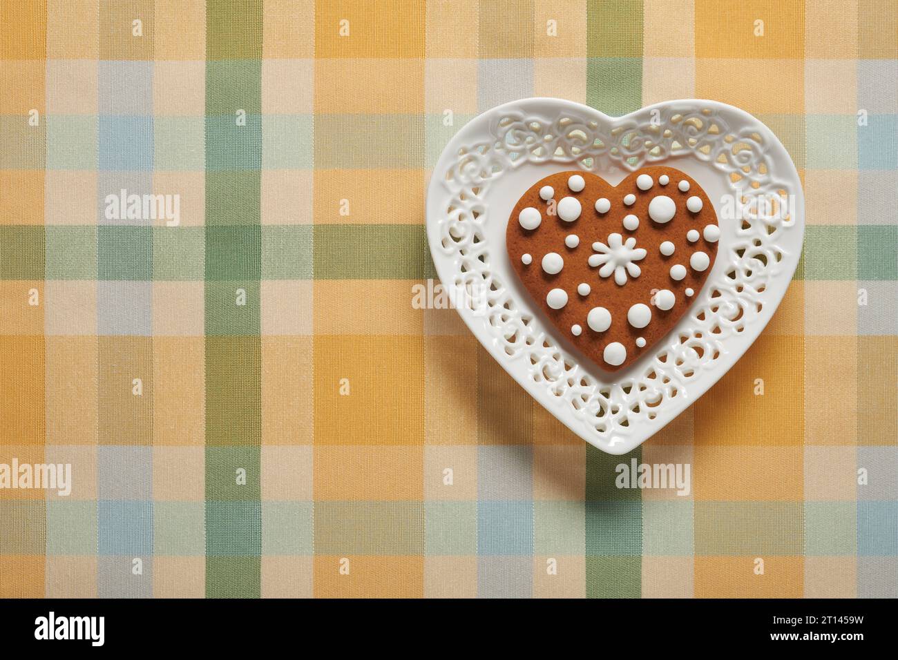 Biscotto dipinto di pan di zenzero a forma di cuore su un piatto a forma di cuore Foto Stock