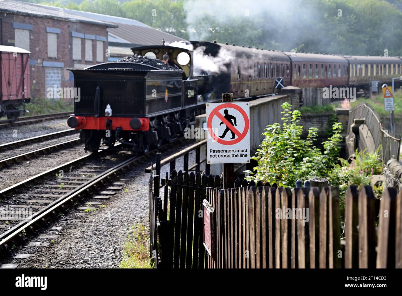 Nota: Si informa i passeggeri di non attraversare la linea alla stazione di Keighley sulla Keighley & Worth Valley Railway, quando si avvicina un treno a vapore. Foto Stock