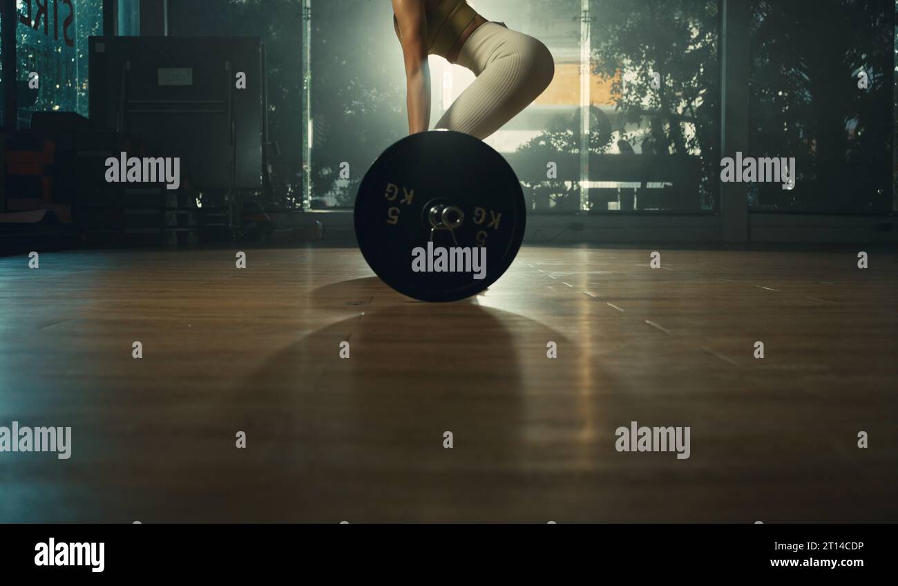 Giovane donna che fa deadlift con barra pesante in palestra, forte atleta femminile con pesi muscolari per il sollevamento del corpo, che si esercita con il campanello. Foto Stock