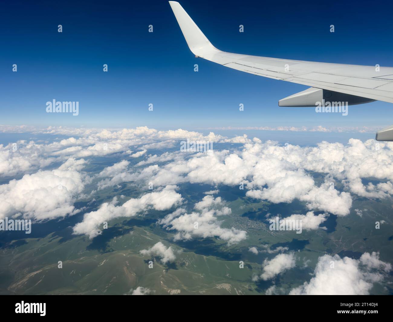 Ala bianca dalla finestra dell'aeroplano con la catena montuosa sottostante nelle giornate di sole. Fantastiche vedute del paesaggio desertico e delle vette innevate dall'aereo Foto Stock