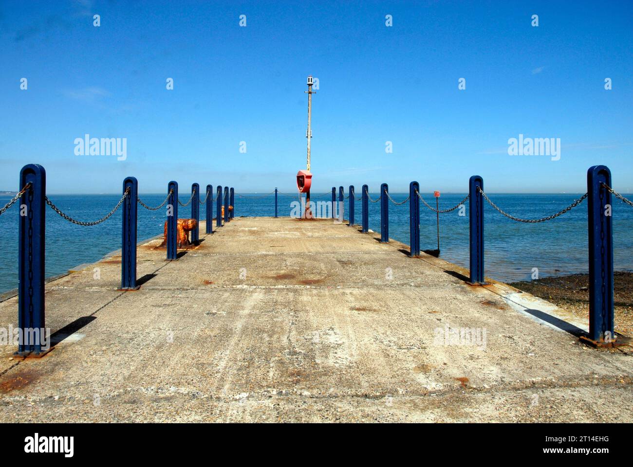 Molo in cemento con pilastri e pali in metallo blu sul bordo e salvagente all'estremità, Whitstable, Kent Foto Stock