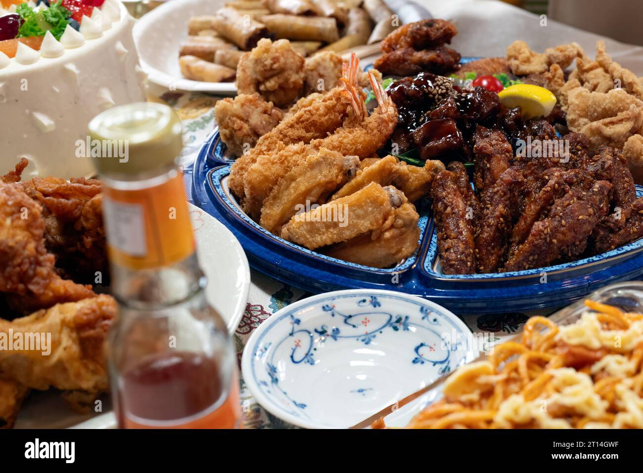 Cibi da festa in tavola con pollo fritto, spaghetti, involtini primavera e salsa al peperoncino. Foto Stock