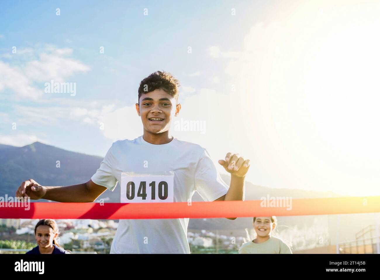 Uomo adolescente corridore che attraversa il traguardo durante la gara di maratona - bambini e stile di vita sportivo Foto Stock