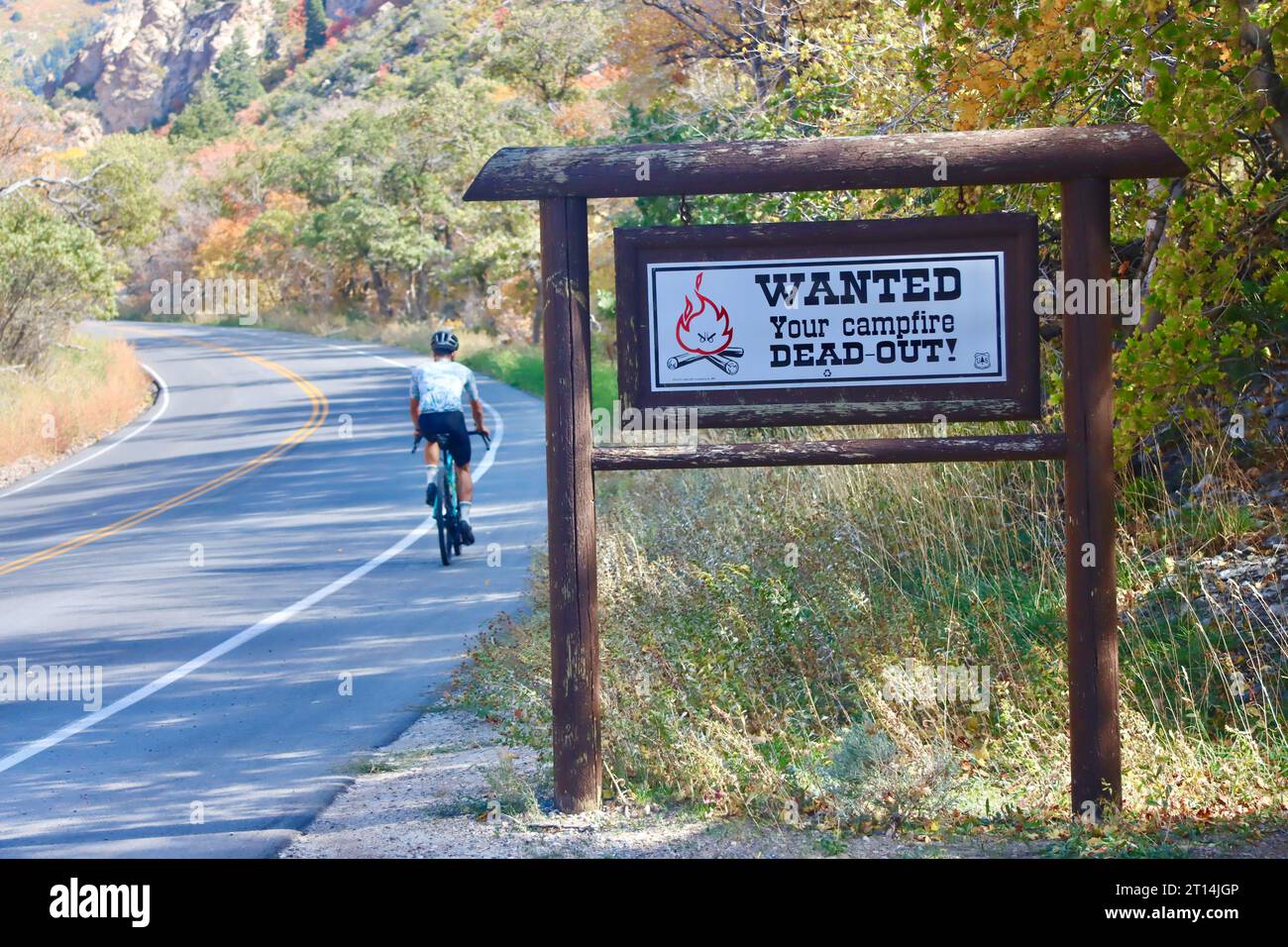Vicino all'ingresso del Millcreek Canyon nello Utah settentrionale, Stati Uniti. in autunno. Un cartello indica che i fuochi sono fuori mentre un ciclista passa. Foto Stock