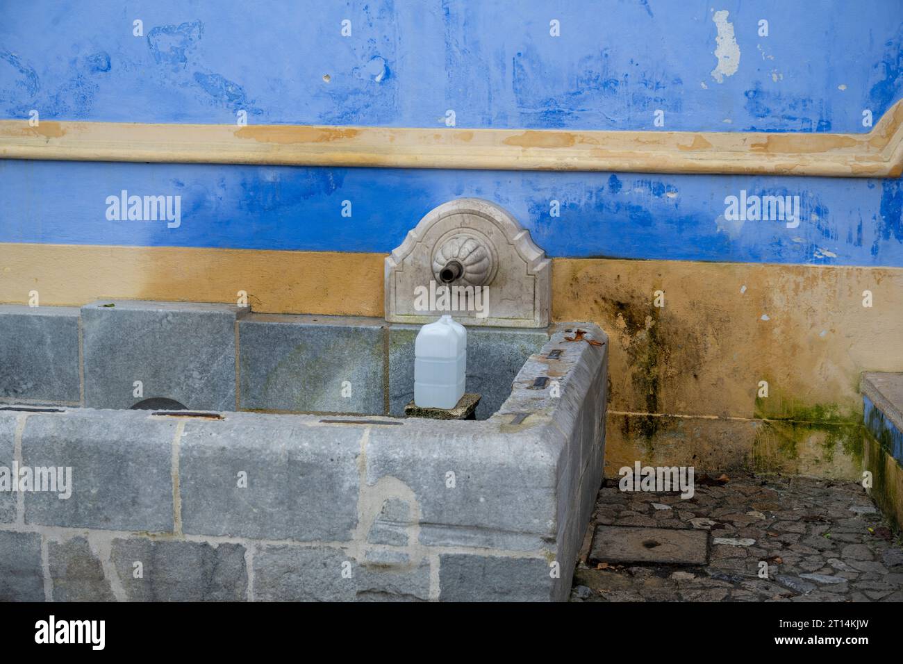 Una donna del posto riempie bottiglie d'acqua di plastica presso la fontana Sabuga a Sintra, Sintra è una città e un comune nella regione della grande Lisbona in Portogallo, Foto Stock