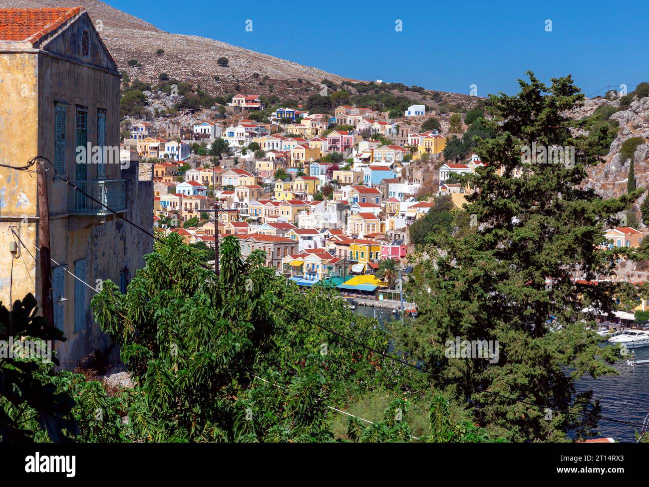 Case tradizionali colorate nel villaggio greco di Symi sulla riva di una baia in una giornata di sole. Grecia. Foto Stock