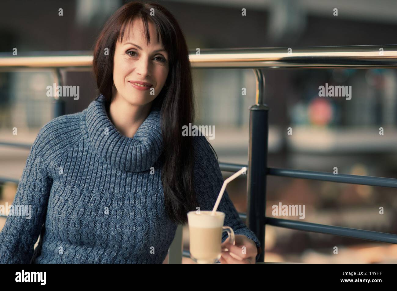 felice donna solitaria che beve caffè al bar Foto Stock