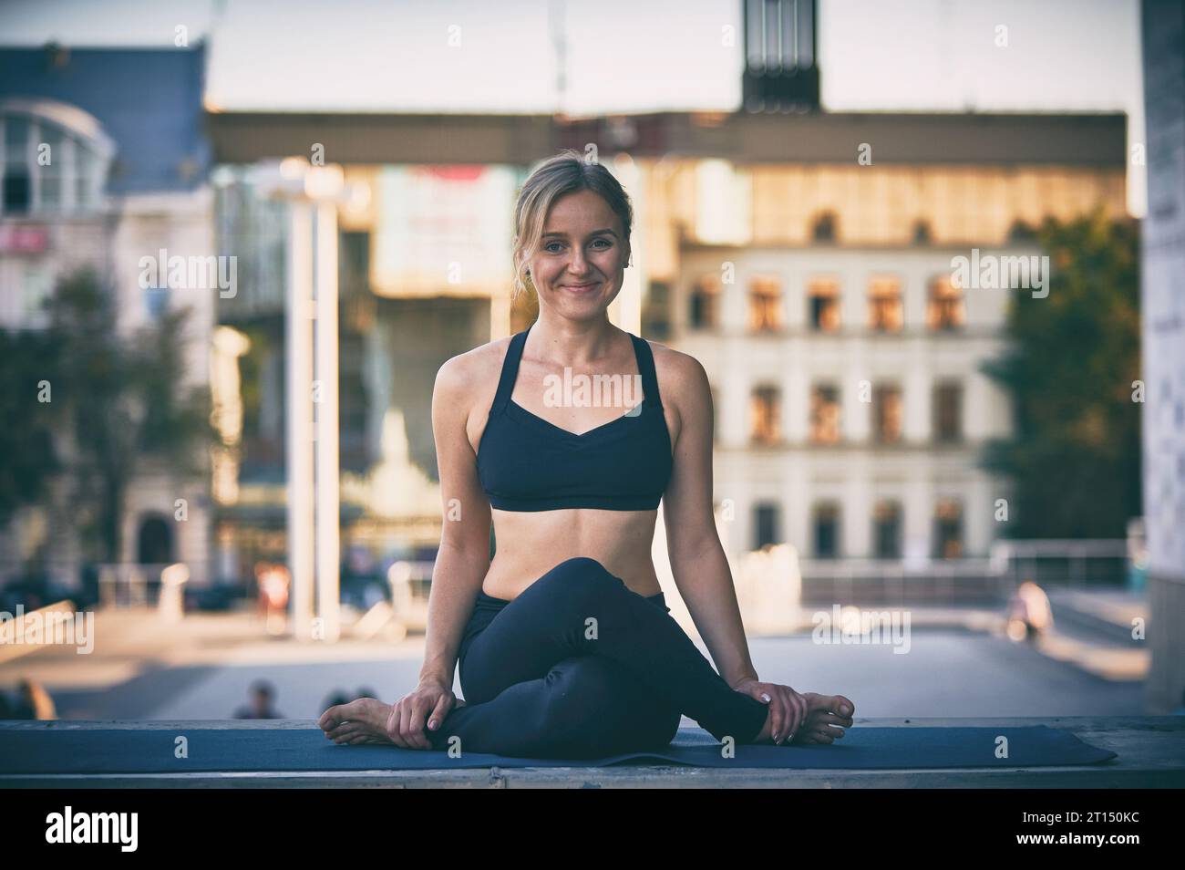 La bella donna yogini sportiva pratica yoga asana in posa per il viso gomukhasana in città Foto Stock