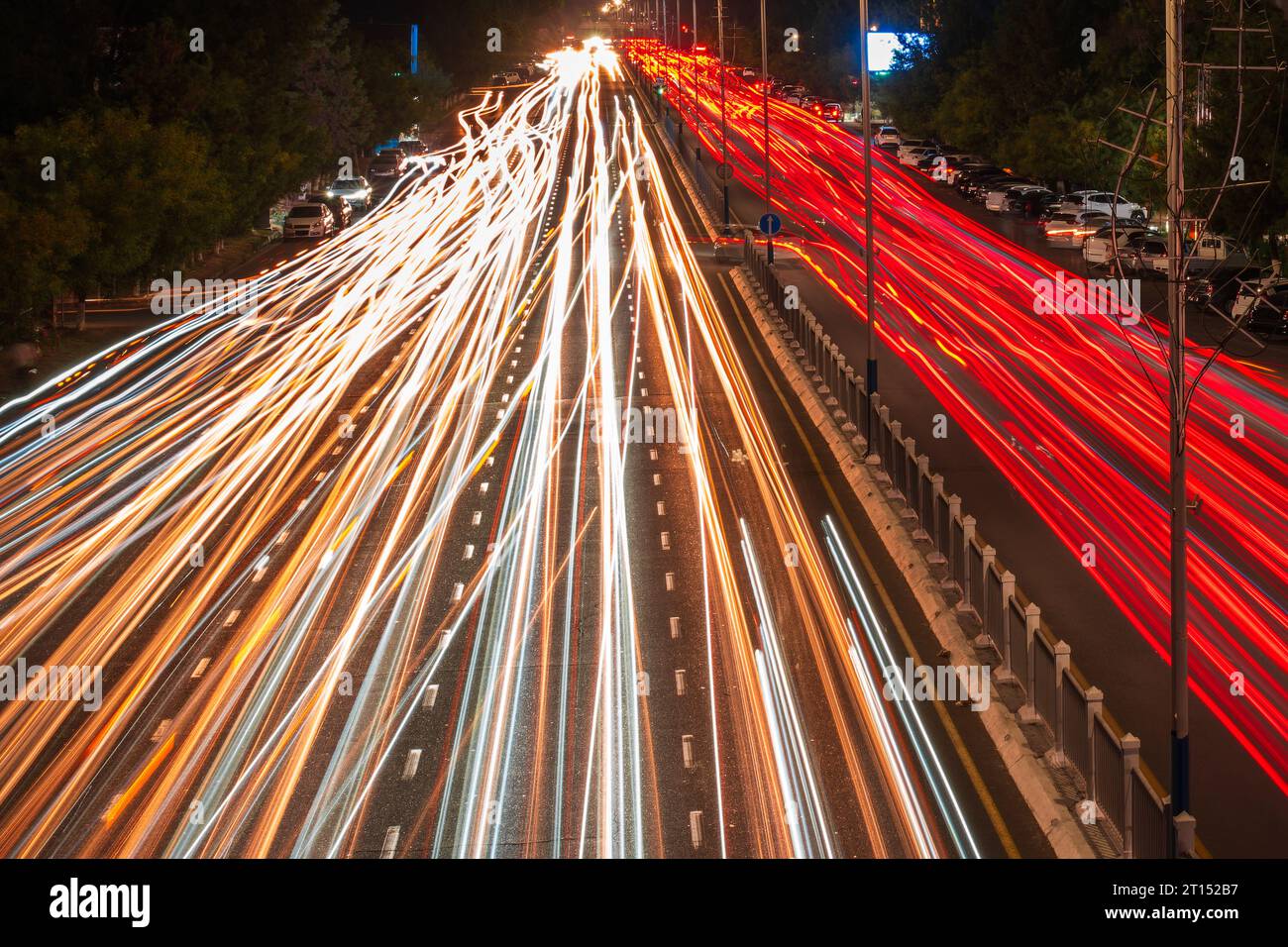 Tracce di fari di auto in movimento sull'autostrada e luci stradali in città di notte. Movimento dell'auto sfocato. Foto Stock