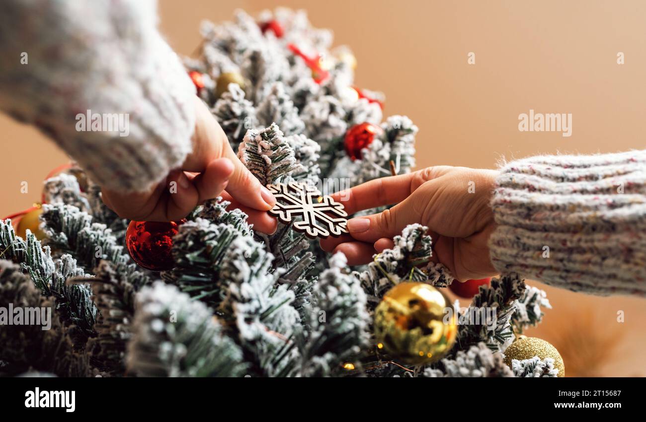 Decorazione dorata dell'albero di Natale nelle mani delle femmine da vicino. Decorare l'albero di Natale. Foto Stock