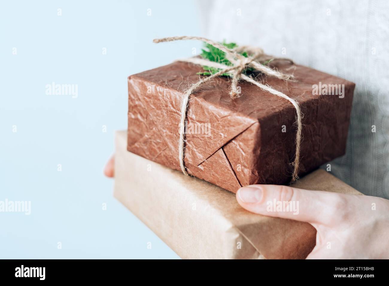 Mani femminili che contengono scatole regalo fatte a mano accuratamente confezionate in confezioni ecologiche. Concetto di vita sostenibile ed eco-consapevole Foto Stock