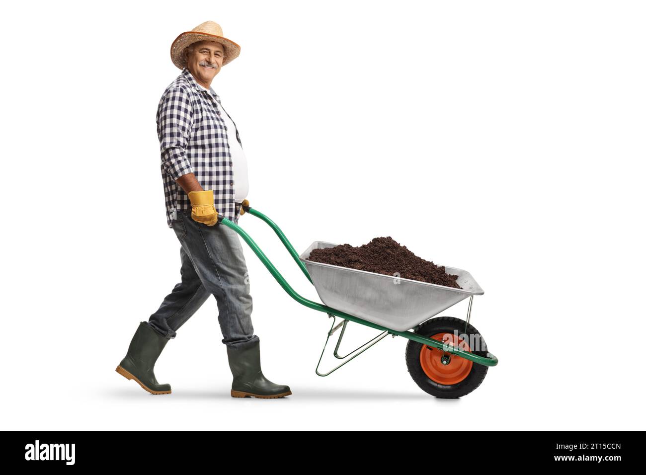 Foto a profilo completo di un giardiniere maturo che spinge una carriola con terra isolata su sfondo bianco Foto Stock