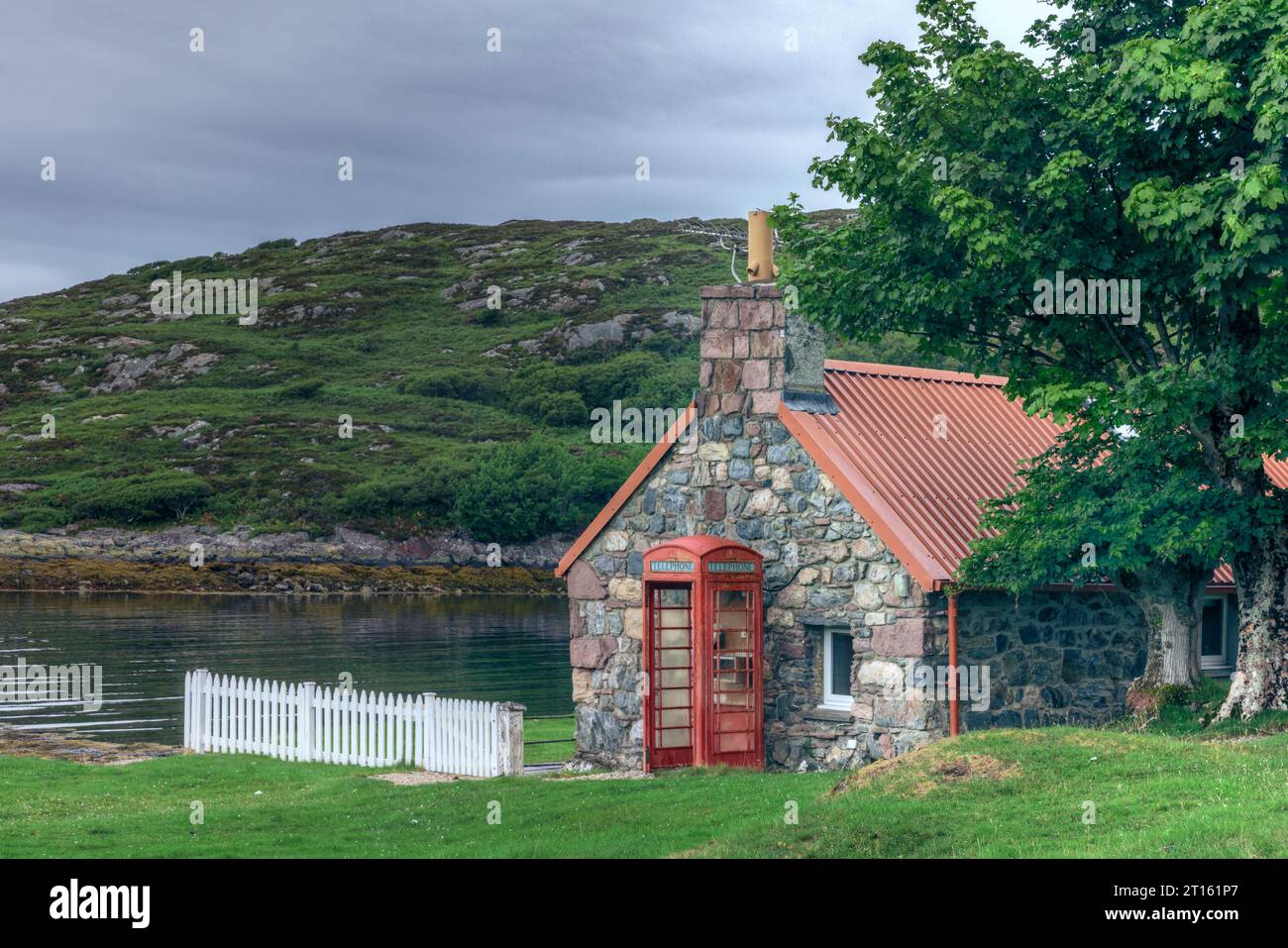 Cabina telefonica tradizionale rossa ai margini di Loch Inver, Sutherland, Scozia. Foto Stock