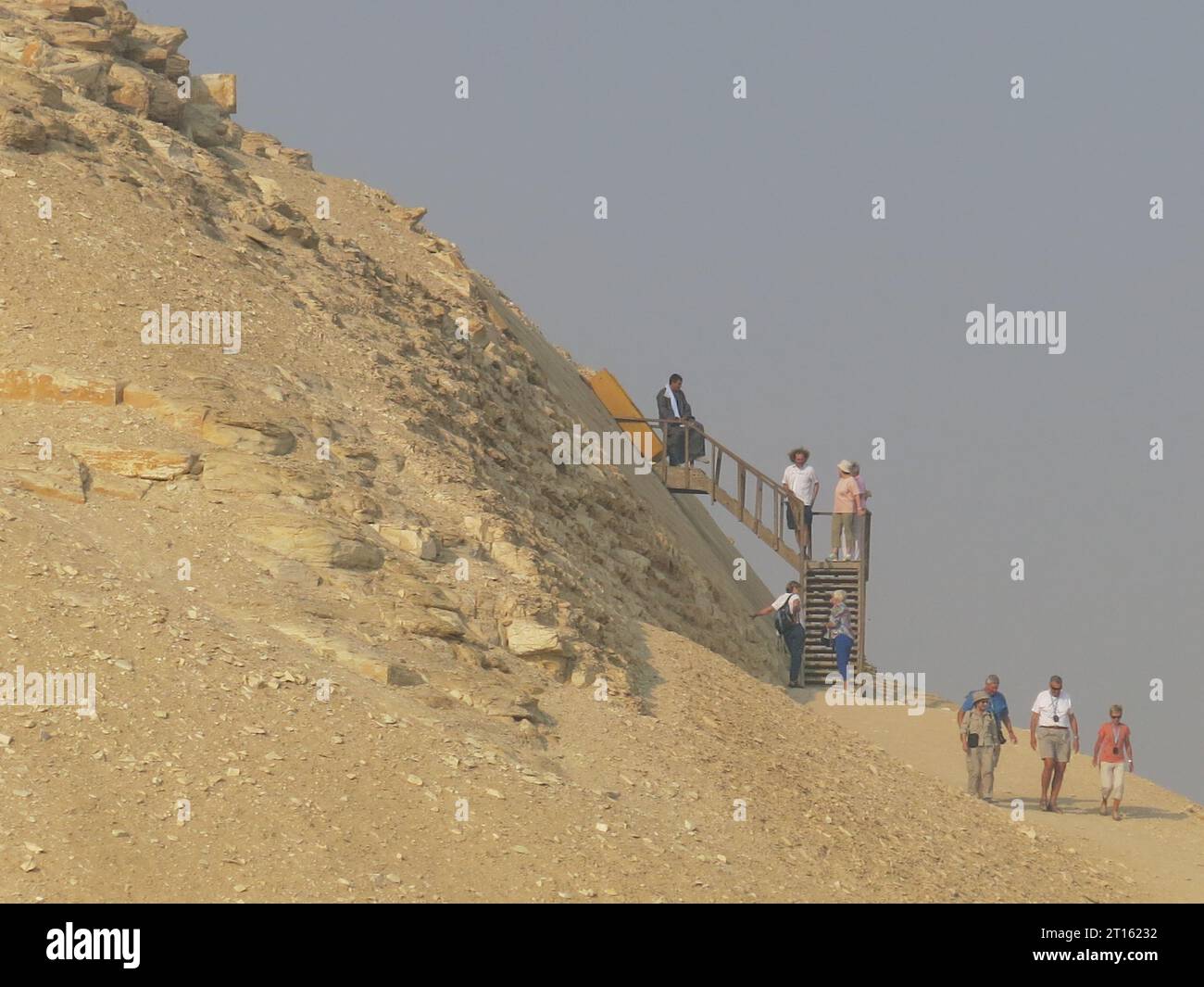 I turisti salgono i gradini fino a metà strada sul lato della piramide Meidum, dove c'è l'ingresso alla camera di sepoltura all'interno. Foto Stock