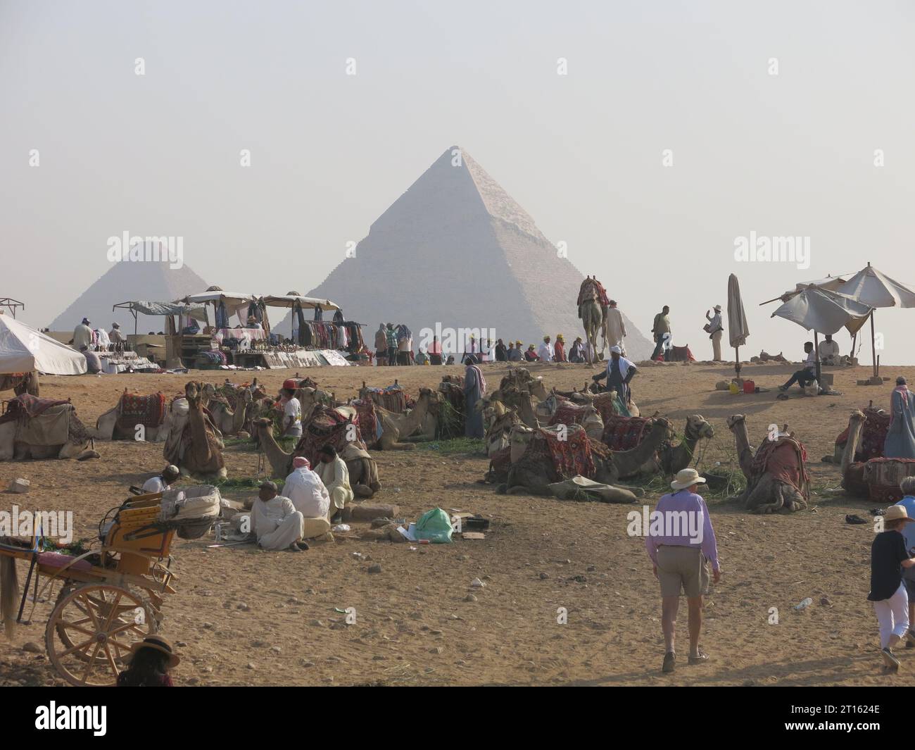 Turismo alle piramidi di Giza in Egitto: La mattina presto e i turisti si radunano tra cammelli, carri e commercianti ai piedi della grande Piramide. Foto Stock