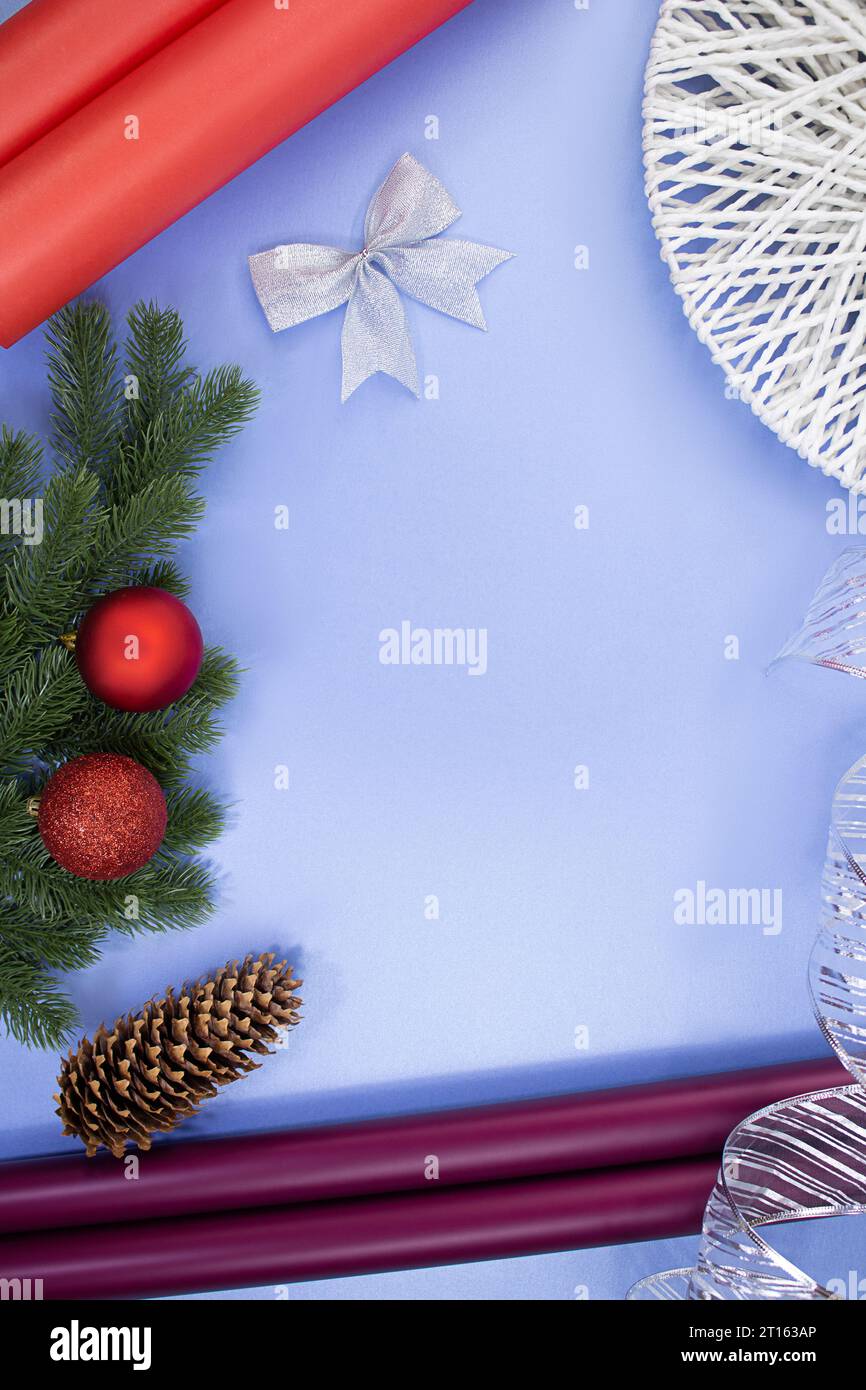 Rotoli di carta, cono di pino, fiocco e nastro, rami di abete con palline di Natale su sfondo blu. Natale di Capodanno. Accessori per confezione regalo Foto Stock