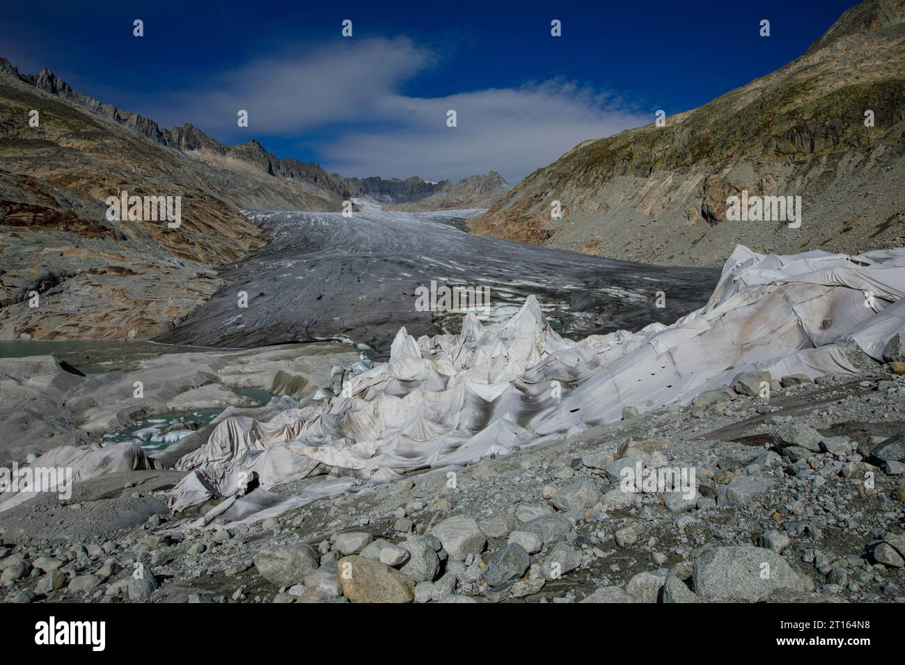 Clima | albedo | Rodano: Enormi coperte di pile coprono parti del ghiacciaio del Rodano in Svizzera nel tentativo di fermare l'inevitabile scioglimento della neve e del ghiaccio. Nel 2018, il ghiacciaio del Rodano (nella foto) si è fuso più di 70 centimetri di spessore. Secondo un recente rapporto dell'Accademia svizzera delle scienze, lo stesso ghiacciaio ha perso oltre 2 metri di spessore nei due anni del 2022/2023. Mentre la neve è un brillante riflesso dell'energia del sole, il ghiaccio più scuro assorbe invece l'energia, accelerando lo scioglimento del ghiacciaio. Il colore e l'oscurità dei ghiacciai variano da un lato all'altro Foto Stock