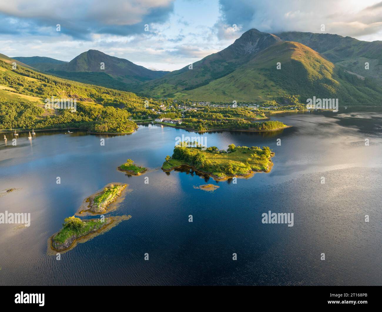 Vista aerea dell'isola di Eilean Munde, dietro di essa il villaggio di Ballachulish con il porto e l'ex cava di ardesia nella parte occidentale di Foto Stock