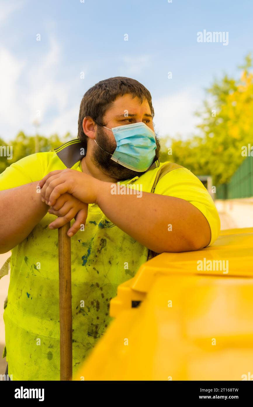 Lavoratore in una fabbrica di riciclaggio o in un punto pulito e spazzatura con una maschera facciale e con protezioni di sicurezza, nuovo normale, pandemia di coronavirus, covid-19. Foto Stock