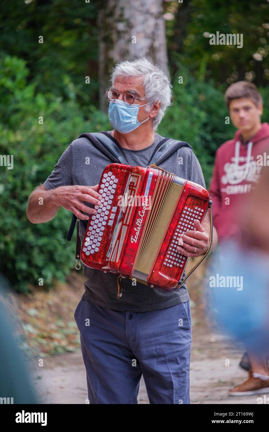 Fisarmonicista che indossa una maschera e suona musica durante il festival estivo di Chatillon en Diois ("Fête des Arts et de la vigne") nel sud della Francia Foto Stock